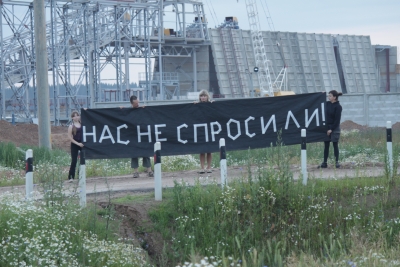 Баннер «Нас не спросили» перед строительной площадкой завода в Островце, Беларусь.